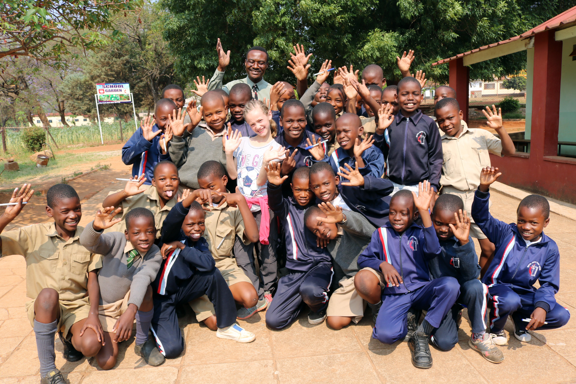 Mikayla Jaissle (center, wearing white soccer shirt) poses with teacher Nicholas Chidzikwe and classmates at Hartzell Primary School. Photo by Eveline Chikwanah.