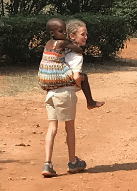 Mikayla Jaissle offers a piggyback ride to a classmate at Hartzell Primary School. Photo by the Rev. Laura Jaissle.
