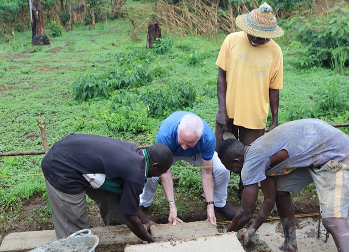 The Rev. Gary Weaver, senior pastor of Camp Hill United Methodist Church in Camp Hill, Pennsylvania, helps to lay one of the first bricks for a new three-classroom building during a groundbreaking ceremony April 27 in Panguma, Sierra Leone. The new structure will help with overcrowding at the village’s Lower Bambara Secondary School. Photo by Phileas Jusu, UMNS.