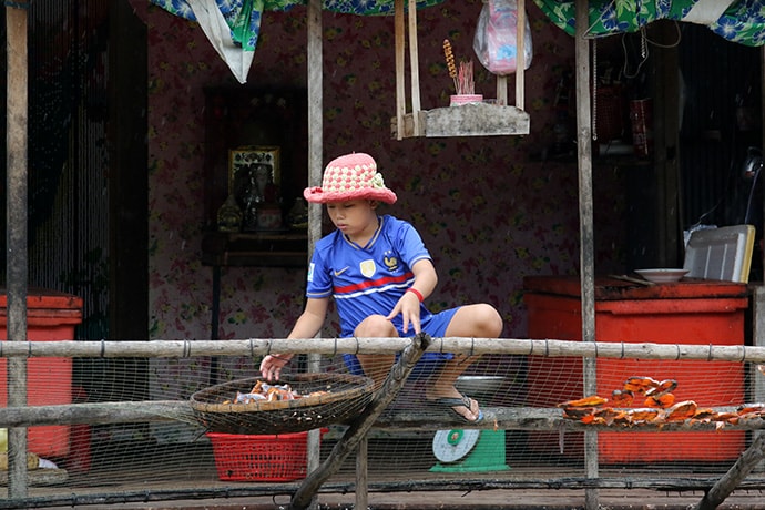 A young girl spreads fish to dry outside her family’s home in a floating village on the Tonle Sap River near Phnom Penh, Cambodia. The United Methodist Board of Global Ministries is planning a program, called Advancing Responsible Khmer, to help prevent human trafficking and to help its survivors feed themselves, educate their children, and afford family homes. Photo by the Rev. Thomas Kim, UM News.