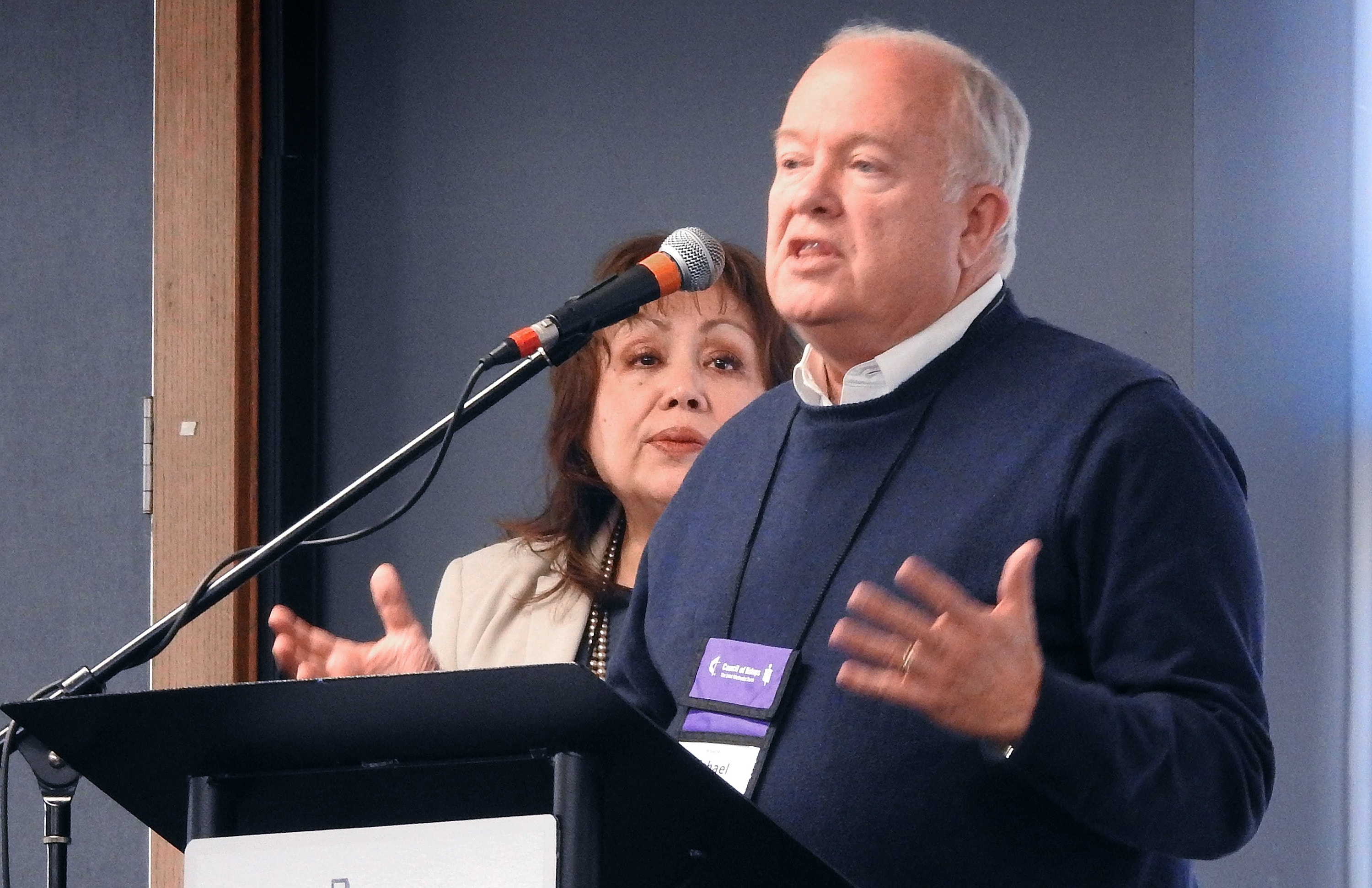 Bishop Michael McKee speaks during the United Methodist Council of Bishops meeting in Lake Junaluska, N.C., where the bishops learned that, at the current rate of giving, the bishops will run out of funds in 2024. McKee is president of the denomination’s General Council on Finance and Administration. With him at the podium is Bishop Minerva Carcaño. Photo by Sam Hodges, UM News.