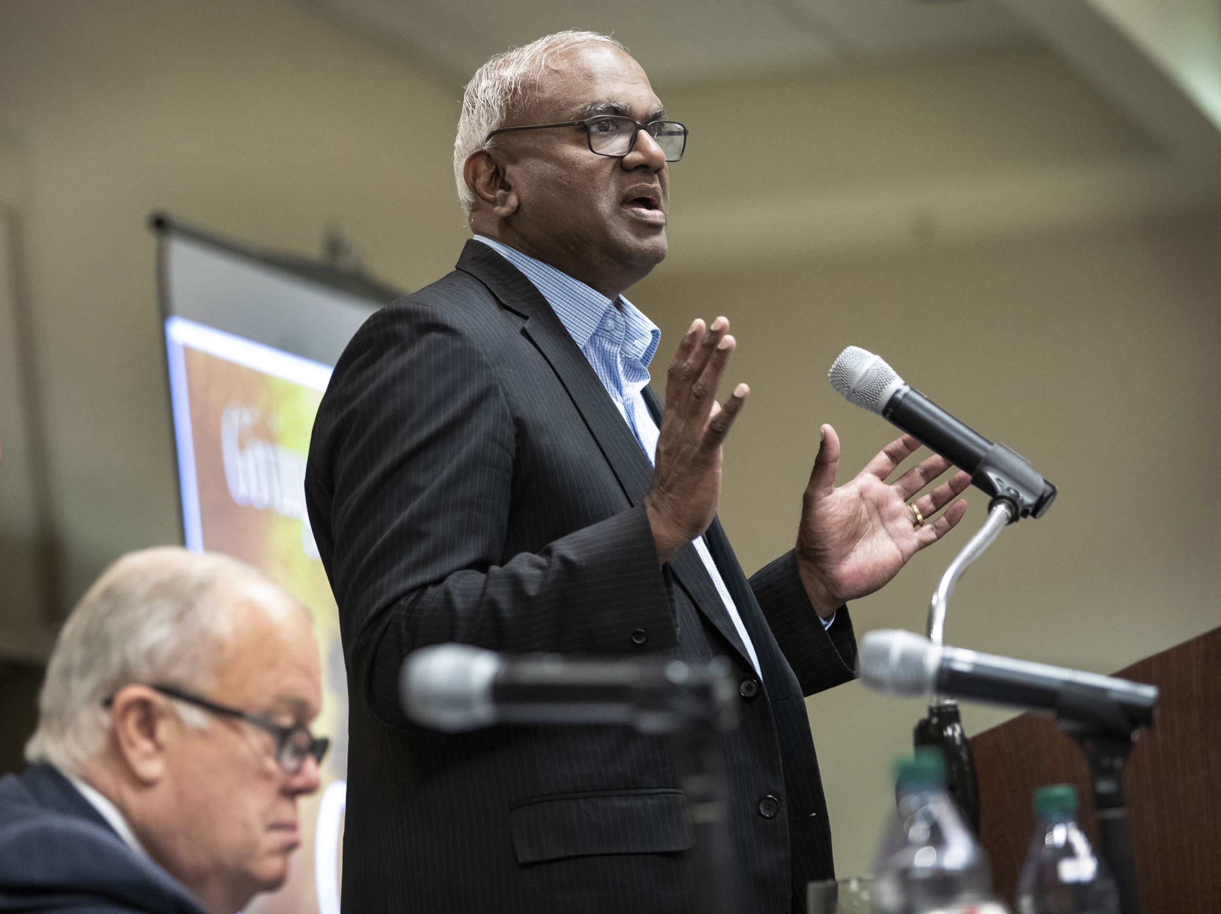 Moses Kumar, top executive of the General Council on Finance and Administration, addresses the Nov. 14-15 meeting of GCFA board of directors held in Nashville, Tenn. Seated is the North Texas Conference’s Bishop Michael McKee, board president. Photo by Kathleen Barry, UM News. 