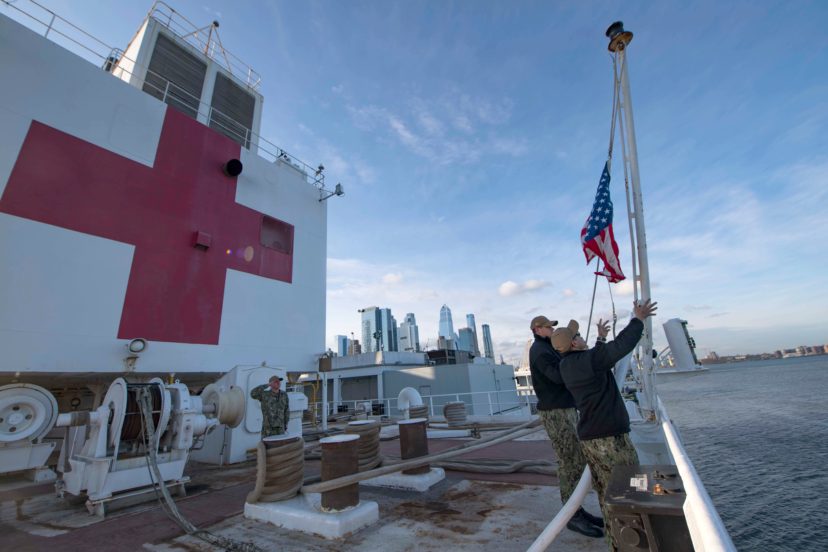 Los marineros en el buque hospital USNS Comfort elevan los colores mientras el barco está amarrado en el puerto de Nueva York en apoyo de los esfuerzos de respuesta COVID-19 de la nación. Los líderes metodistas unidos están pintando una imagen aleccionadora del impacto del coronavirus en Nueva York y Nueva Jersey. "Este es nuestro nuevo 11 de septiembre en Nueva York", dijo el obispo del área de Nueva York Thomas J. Bickerton. Foto cortesía de Sara Eshleman, Marina de los EE. UU.