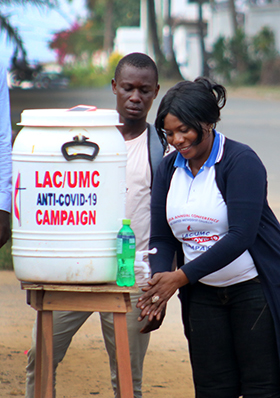 Lango W. Toe, directrice de santé de l'Église Méthodiste Unie du Libéria, fait une démonstration de lavage des mains dans l'une des stations installées dans les rues de Sinkor, au Libéria. Photo de E Julu Swen, UM News.