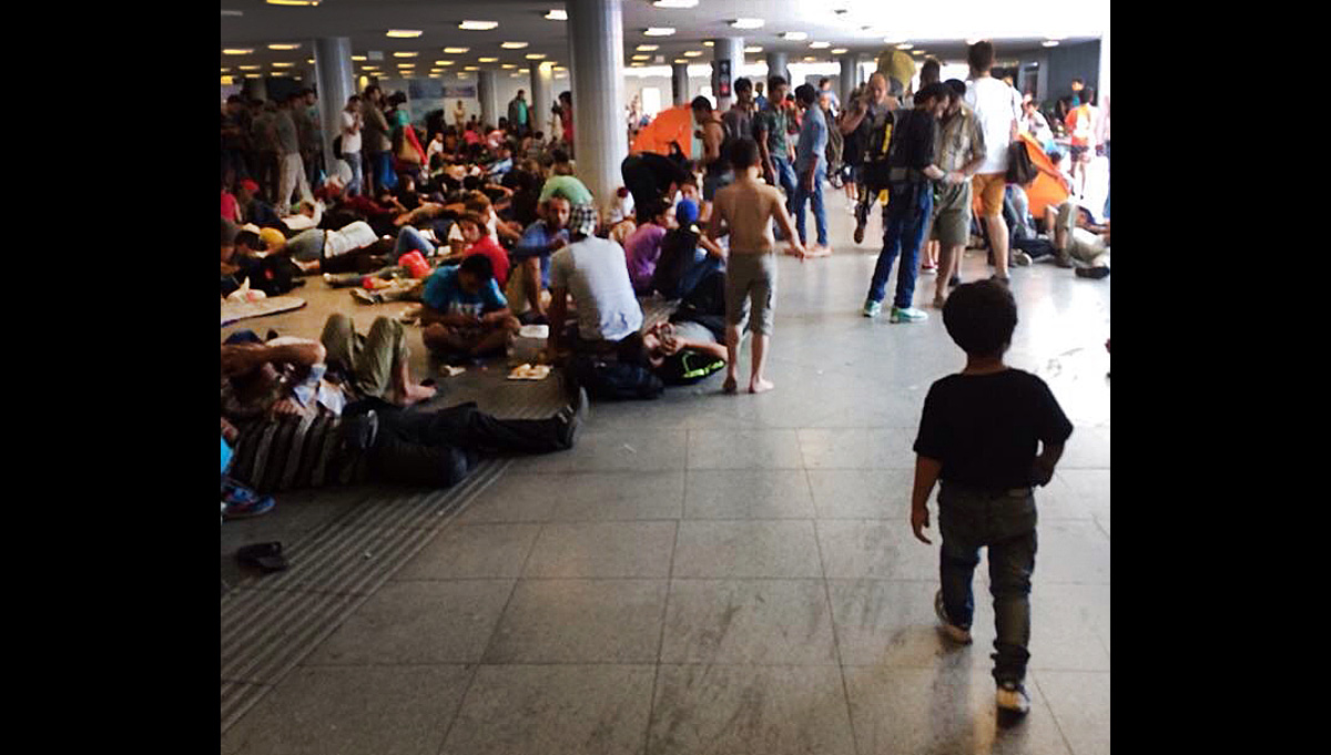 Train passengers, including migrants, wait Sept. 2 at the Keleti pályaudvar station in Budapest in hopes of boarding trains to other countries in western Europe. Some, frustrated with waiting, scuffled with police outside the station, according to news reports.  Photo by Daniel Peters for UMNS