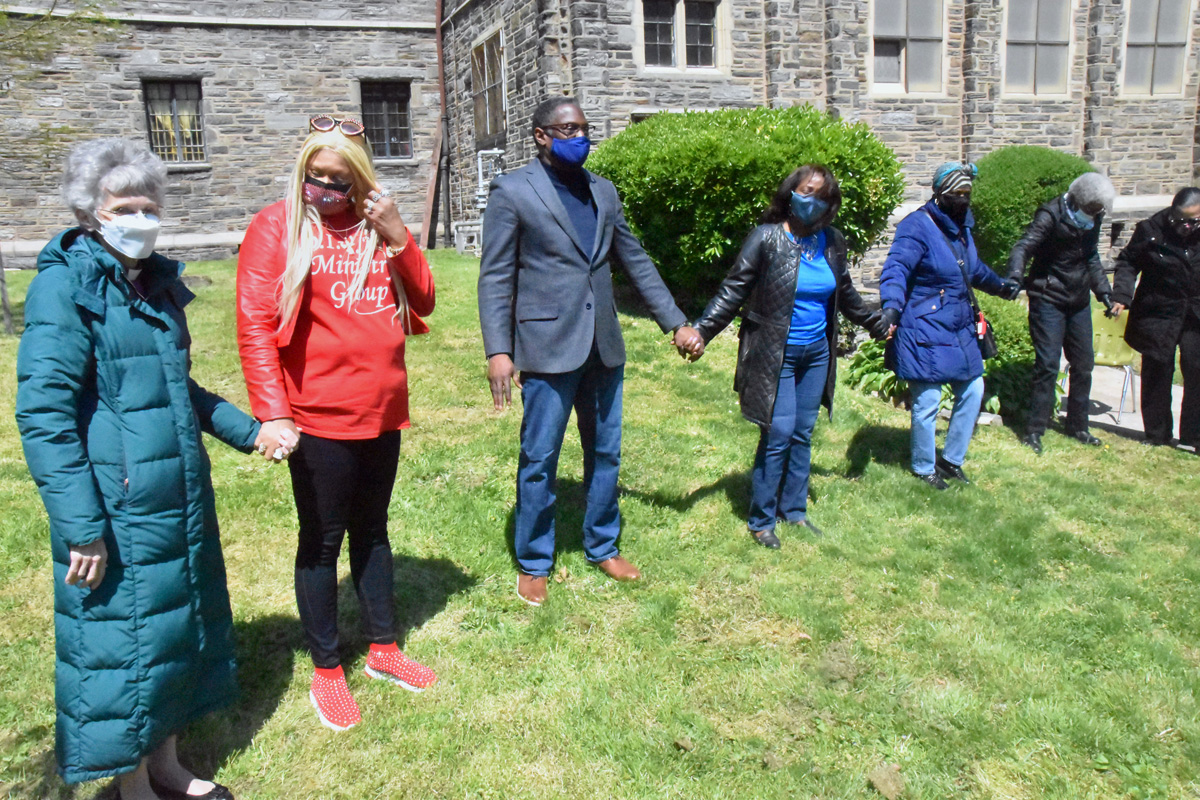 A partir da esquerda: a Bispa do Leste da Pensilvânia Peggy Johnson ora com a Revda. Jeanette Davis, o Rev. Gregory Holston e sua esposa, Deborah Holston, e outros no gramado da Igreja Metodista Unida Memorial de Janes na Filadélfia, durante uma vigília de oração inter-religiosa em abril 23. O Clero Negro da Filadélfia e arredores convocou os pastores da cidade para liderar orações em ou perto de suas casas de culto em meio a uma onda de violência armada na área da Filadélfia. Foto de John W. Coleman, Notícias MU.