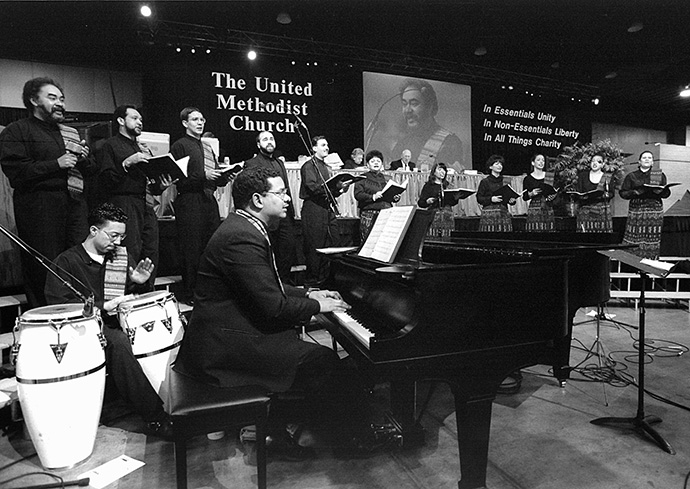 Jorge Lockward toca piano e dirige o Coral Metodista Unida Hispana de Nova York enquanto os delegados e visitantes da Conferência Geral Metodista Unida de 1996 em Denver cantam do Mil Voces Para Celebrar. Foto de arquivo por Mike DuBose, UM News.