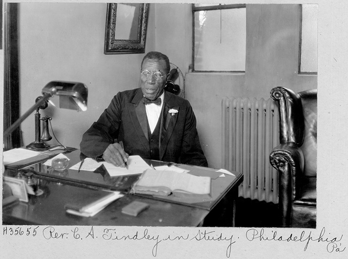 Le révérend C. A. Tindley travaille dans son bureau à Philadelphie. Tindley a été pasteur de l’Église épiscopale Méthodiste et a été un compositeur de musique gospel renommé. Photo © La Commission Méthodiste Unie pour les Archives et l’Histoire.