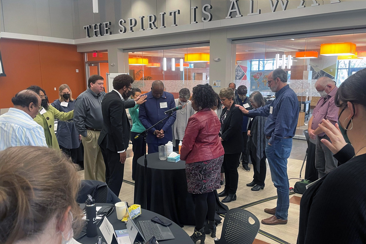 Members of the Connectional Table lay hands on Bishop Mande Muyombo (center), chair of the Connectional Table, and Judi Kenaston (fourth from right), interim chief connectional ministries officer, during the group’s meeting Feb. 24 in Atlanta. The leadership body helps determine the budget of The United Methodist Church. Photo by Jim Patterson, UM News.