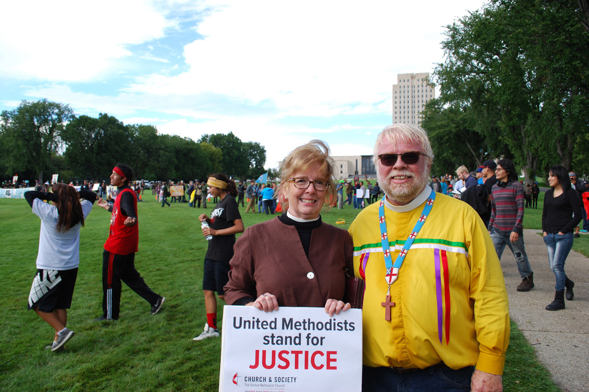 Susan Henry-Crowe, top executive of the United Methodist Board of Church and Society, and Fr. John Floberg, rector of Episcopal churches St James, St. Luke's and Church of the Cross on the Standing Rock nation, stand outside the North Dakota state capitol grounds in Bismark in 2016. Henry-Crowe retired on Dec. 31, 2022, after eight years leading Church and Society and almost 49 years of active ministry in The United Methodist Church. File photo by John Hill, Church and Society.