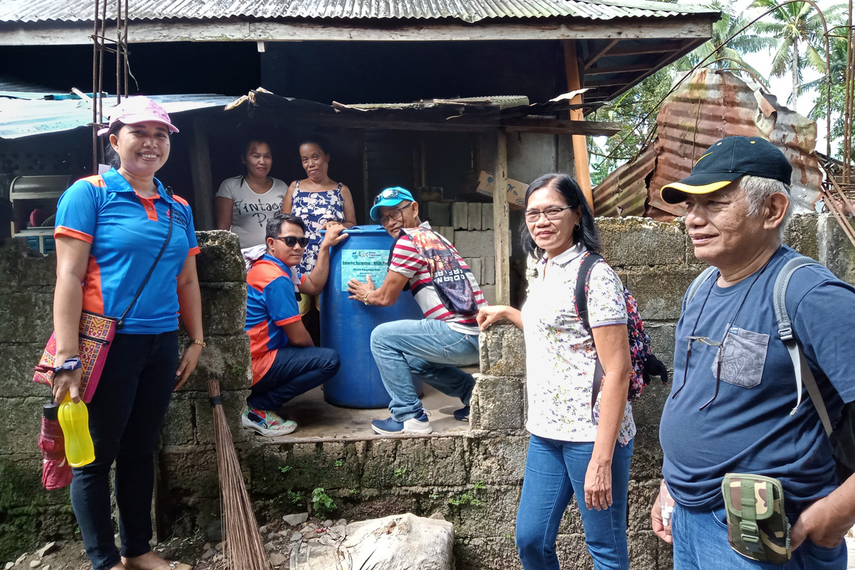 United Methodist pastors and disaster management team leaders evaluate a rainwater-harvesting tank that was installed a month earlier in the Novele community in the Davao Area of the Philippines. The United Methodist Church distributed the drums to more than 30 households and three community centers in the region. Pictured (from left to right) are the Rev. Marlyn N. Nabatilan, an unnamed neighbor, recipient Janeth Erandio, the Rev. Jerson Sanggo and team leaders Eddie Danglapen, Fe Tomas and Maurice Bigaran. Photo courtesy of the Rev. Dan Reuben L. Sison.