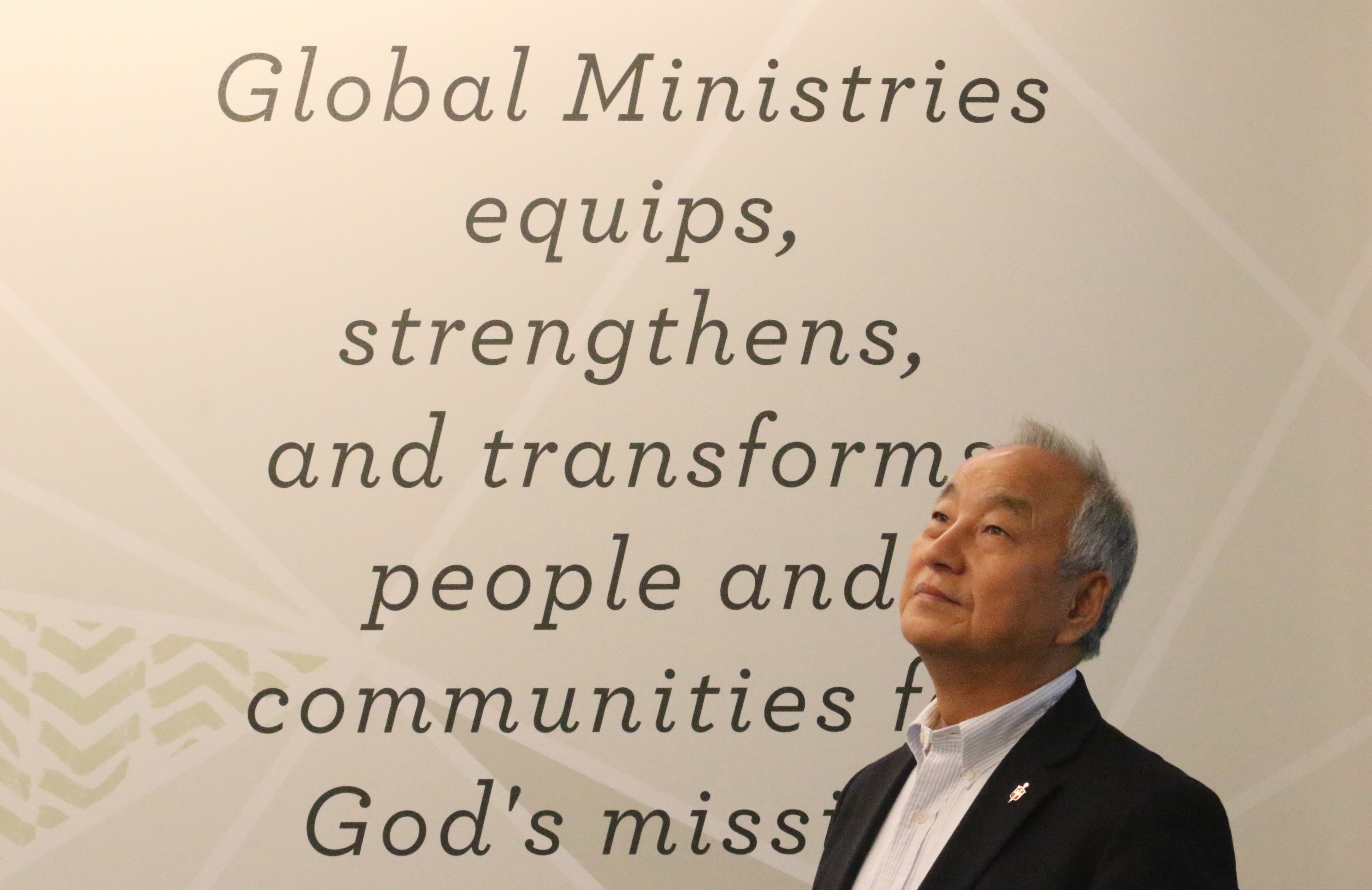 연합감리교회 세계선교부 이사장인 정희수 감독이 2022년 9월 29일 한인목회강화협의회 연례 회의 중 세계선교부 사무실 벽에 쓰인 “세계선교부는 이 세상에서 하나님의 선교를 위해 사람들과 지역공동체를 겸비(equip)시키고, 힘을 주고, 변화시킨다.”라고 쓰인 구호 앞에 서 있다. 사진, 김응선 목사, 연합감리교뉴스.