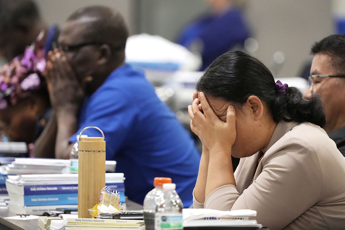 General Conference delegates pray as Bishop Connie Shelton of the Raleigh Episcopal Area leads a prayer for victims of a deadly shooting in east Charlotte on April 29. Photo by Larry McCormack, UM News.