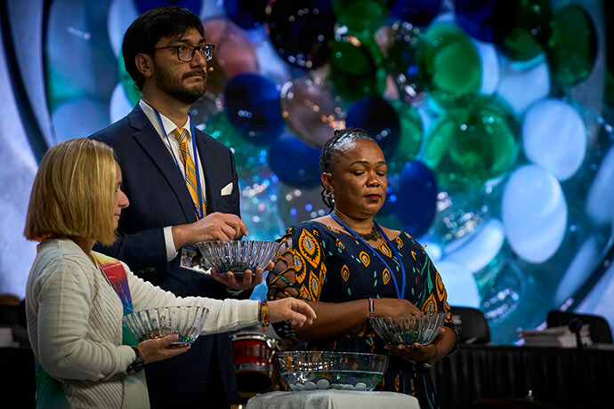 Durante un servicio conmemorativo el 1 de mayo, participantes en la Conferencia General Metodista Unida reunida en Charlotte, Carolina del Norte, arrojan piedras en un recipiente con agua en memoria de los/as obispos/as, cónyuges y delegados/as que han muerto desde la última Conferencia General. Foto de Paul Jeffrey, Noticias MU.