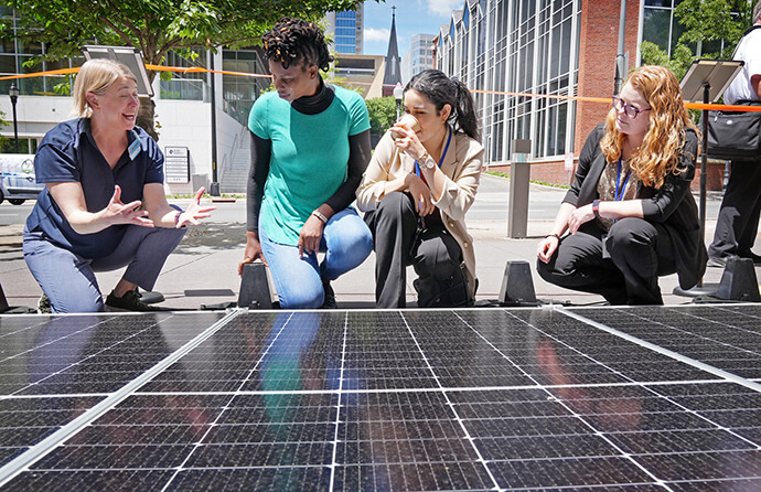 The Rev. Jenny Phillips, director of environmental sustainability with the United Methodist Board of Global Ministries, talks with Shamiso Mupara, Ilka Vega and Megan Hale about the Mobile Solar Power Station on display at the United Methodist General Conference in Charlotte, N.C., on May 1. Photo by Larry McCormack, UM News.