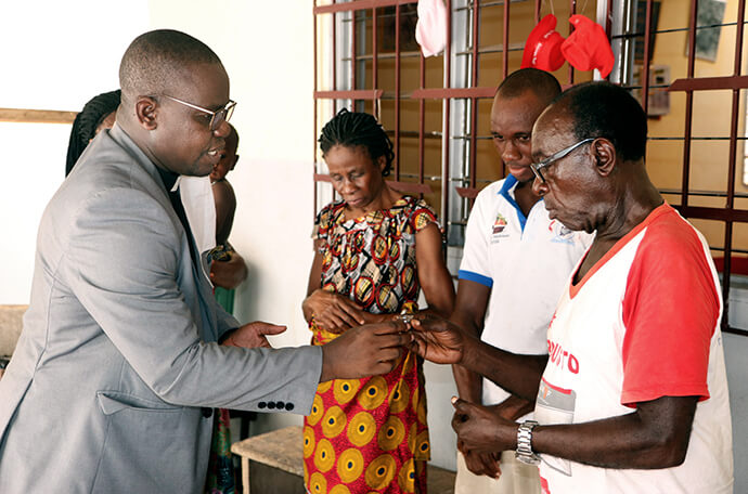 O Rev. Isaac Broune (à esquerda), pastor da Igreja Metodista Unida Bethel no bairro de Elephant, no sul de Abidjan, Costa do Marfim, partilha a comunhão com a família Ohouo (da esquerda, Appolos, Fabrice, Chiadon e Chantal) durante um serviço religioso em suas casas em 2020. Enquanto as igrejas estavam fechadas por causa da pandemia da COVID-19, os membros realizavam cultos em casa com recursos fornecidos pelos seus pastores. Foto de arquivo de John Mel, Notícias MU.