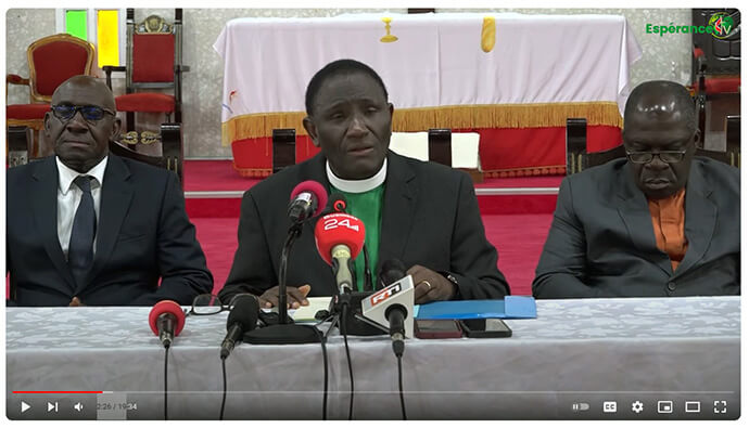 Au centre, le Révérend Isaac Bodjé, secrétaire de la Conférence de Côte d'Ivoire, lit une déclaration à la presse locale expliquant que la Conférence de Côte d'Ivoire se retire en raison des changements apportés par la récente Conférence Générale. Il est accompagné d'autres responsables de la conférence. Capture d'écran avec l'aimable autorisation de la Conférence de Côte d'Ivoire via YouTube par UM News.