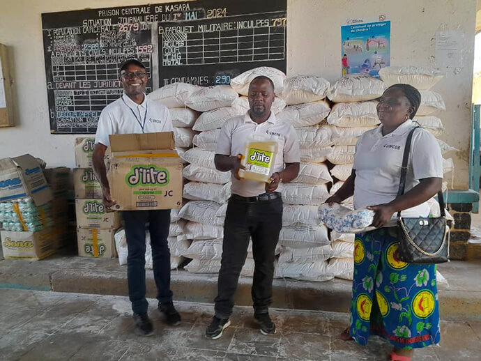 Le révérend Caleb Mbaz (à gauche), coordonnateur du Bureau de Gestion des Catastrophes pour la Région Épiscopale du Sud du Congo et Zambie, transporte une boîte contenant de l'huile végétale pour les détenus de la prison centrale de Kasapa, près de Lubumbashi, au Congo. Les membres de l'équipe de gestion des catastrophes Kasongo Kilundu Olivier et Louise Tshiwengo se joignent à lui. L'Église Méthodiste Unie du Sud du Congo a distribué plus de 16 tonnes de nourriture United Methodist Committee on Relief (Comité Méthodiste Uni de Secours Comité Méthodiste Uni de Secours). Photo par Christian Kasweka, UM News.