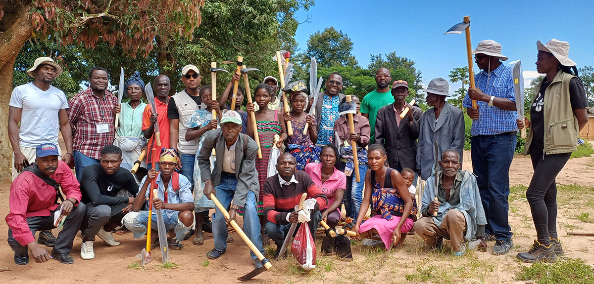 Homens e mulheres da comunidade de Kimbamba e membros do Projecto Yambasu depois da distribuição de ferramentas de produção. Kimbamba, Milange. Foto de João Nhanga.