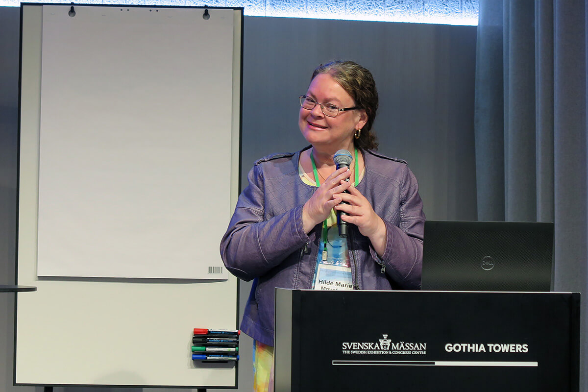 La Revda. Dra. Hilde Marie Movafagh, teóloga y rectora del Seminario Teológico de la Iglesia Metodista Unida en Oslo, Noruega da la bienvenida a los/as participantes en la reunión de la Asociación Internacional de Escuelas, Colegios y Universidades Metodistas, celebrada del 11 al 13 de agosto en Gotemburgo. Suecia. Movafagh también es miembro de la junta directiva de la asociación. La reunión, que tuvo lugar inmediatamente antes de la Conferencia Metodista Mundial, atrajo a unos/as 100 académicos/as y administradores/as universitarios/as de diferentes denominaciones metodistas de todo el mundo. Foto de Heather Hahn, Noticias MU.