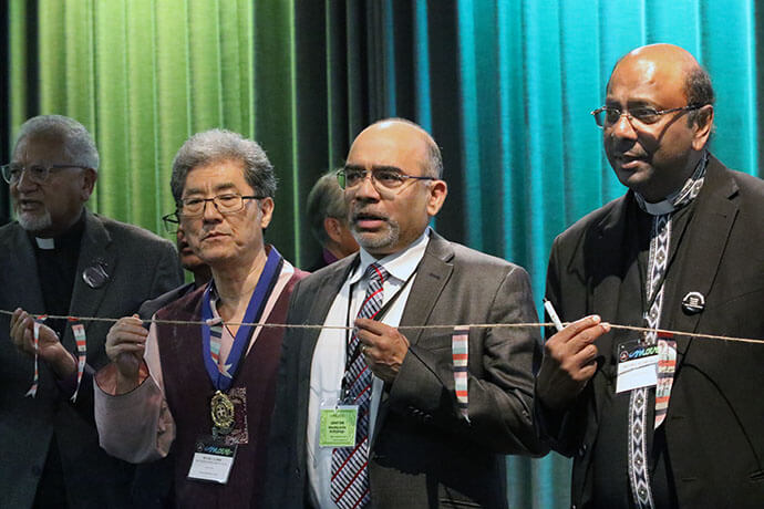 Bishop Ivan Abraham (from left), outgoing general secretary of the World Methodist Council; the Rev. Jong Chun Park, president of the World Methodist Council; Roland Fernandes, top executive of the United Methodist Board of Global Ministries; and the Rev. Jerry Pillay, general secretary of the World Council of Churches, hold a prayer line for peace at the Korea Peace Night gathering Aug. 15 during the World Methodist Conference in Gothenburg, Sweden. Photo by the Rev. Thomas E. Kim, United Methodist News.