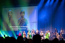 Os irmãos Agnes e Alfred Quint (na tela) se juntam aos cantores da Uniting Church na Suécia para liderar os adoradores em “O Store Gud”, o nome sueco original do hino que os falantes de inglês conhecem como “How Great Thou Art”, durante a World Methodist Conference em Gotemburgo, Suécia. Foto de Klaus Ulrich Ruof, Germany Central Conference. Os irmãos Agnes e Alfred Quint (na tela) se juntam aos cantores da Uniting Church na Suécia para liderar os adoradores em “O Store Gud”, o nome sueco original do hino que os falantes de inglês conhecem como “How Great Thou Art”, durante a World Methodist Conference em Gotemburgo, Suécia. Foto de Klaus Ulrich Ruof, Germany Central Conference.