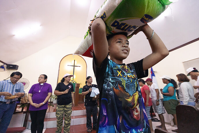 An aid recipient carries a bag of rice from Rosario United Methodist Church in Cavite Province in the Philippines. The Disaster Management Office of the Manila Episcopal Area, in collaboration with the United Methodist Committee on Relief, provided the aid for families affected by Typhoon Carina. Photo by Mike DuBose, UM News.
