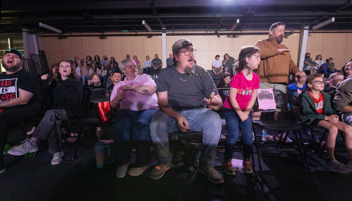 El Rev. Steven Barber al centro con su hija, Gwenivere, observan la acción de la lucha libre profesional desde sus asientos el 2 de noviembre en el Centro de Eventos de Priceville, Alabama. 