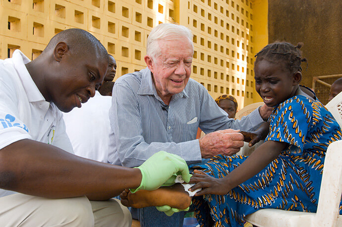 Jimmy Carter consoles a young patient having a worm removed from her body in Savelugu, Ghana, in February 2007. The Carter Center leads the international campaign to eradicate Guinea worm disease. Photo courtesy of The Carter Center.