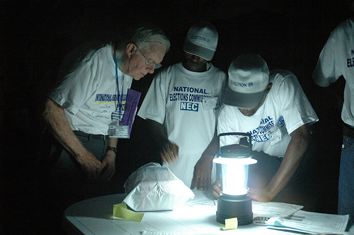 Jimmy Carter witnesses ballot counting by lamplight at a polling station in Liberia during The Carter Center’s observation of presidential elections on Oct. 11, 2005. Photo courtesy of The Carter Center.