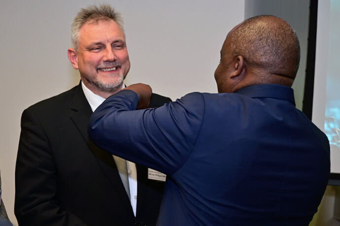 Bishop Mande Muyombo places the bishop's pin on the Rev. Werner Philipp's lapel after he was elected a United Methodist bishop at the Germany Central Conference on Feb. 13 in Würzburg, Germany. Photo by Klaus Ulrich Ruof, EmK Public Relations.