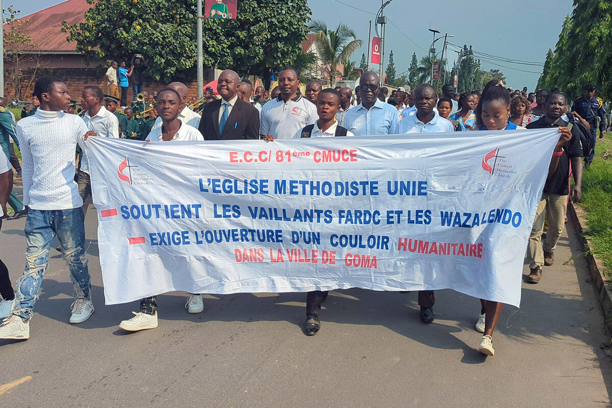 Young people hold a banner during a rally for peace in Kindu, Congo, in early February. Behind them, United Methodist clergy and other young people march to demand peace in eastern Congo, where fighting between M23 rebels and the Congolese army has escalated in recent months. Photo by Chadrack Tambwe Londe, UM News.