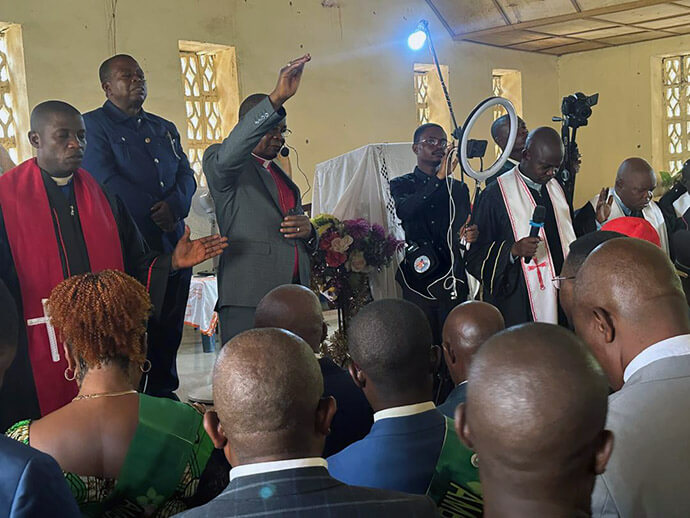 East Congo Bishop Gabriel Yemba Unda (with his hand raised) prays during a multichurch service in February. Unda is surrounded by clerics of other religious denominations who joined together to call for peace in the region. Photo by Judith Osongo Yanga, UM News.