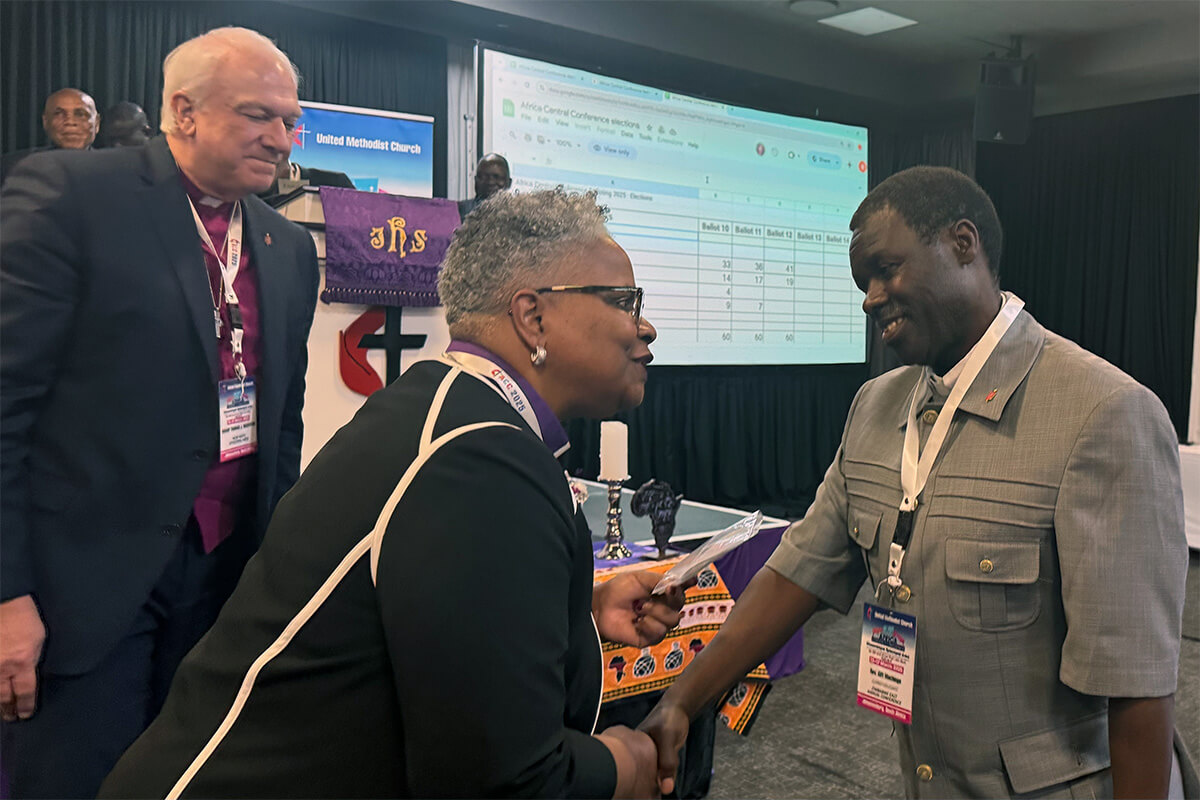 O Rev. Gift Machinga (à direita), recém-eleito bispo, recebe saudações da Bispa LaTrelle Easterling enquanto o Bispo Thomas Bickerton observa. A Conferência Central da África elegeu Machinga do Zimbábue como bispo em 15 de março. Foto de Priscilla Muzerengwa, Comunicações Metodista Unida.