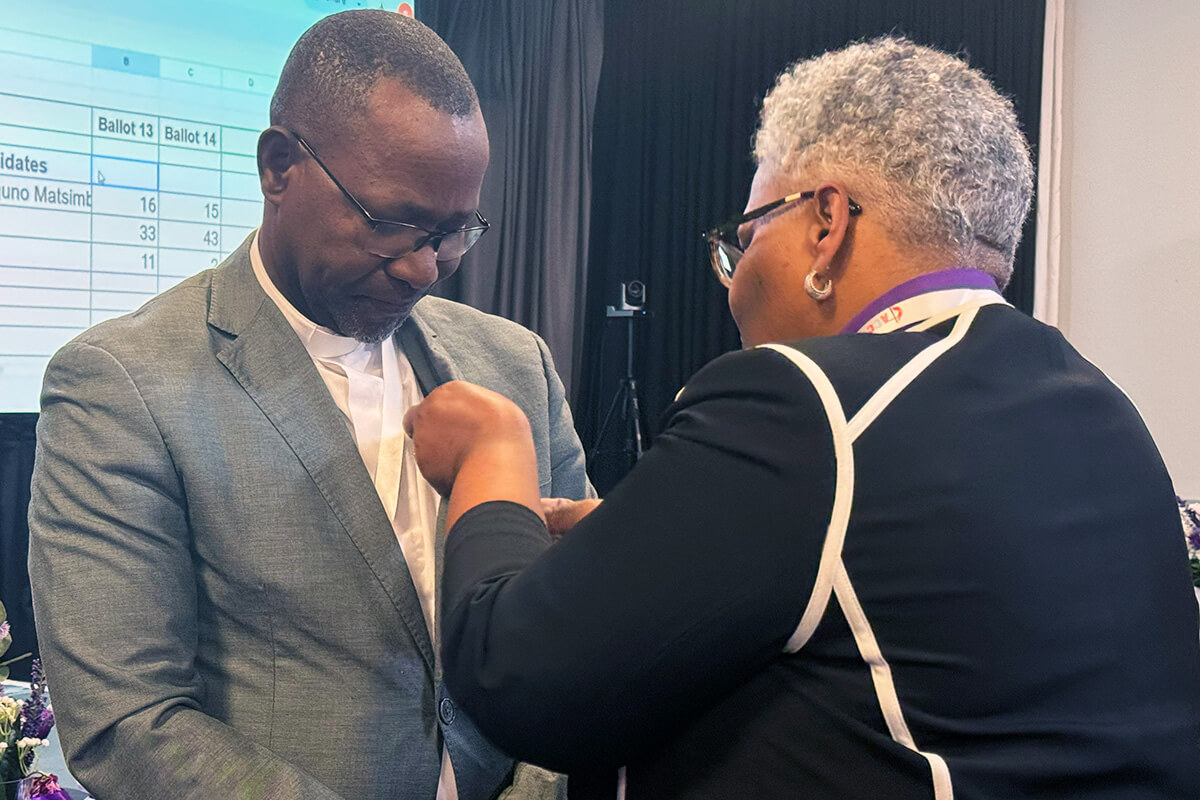 O Rev. João Filimone Sambo de Moçambique recebe o broche episcopal Metodista Unido do Bispo LaTrelle Easterling. Sambo foi eleito bispo em 15 de março pela Conferência Central da África. Foto de Priscilla Muzerengwa, Comunicações Metodistas Unido.