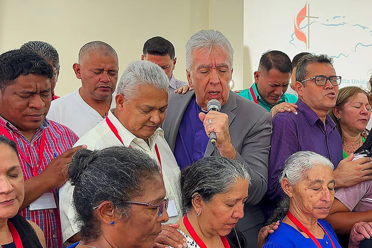 Bishop Rubén Saenz (center) prays for delegates to the annual meeting of the United Methodist Mission in Honduras during the closing session on March 18 in Tegucigalpa, Honduras. Saenz is the mission’s newly appointed episcopal leader. Photo by the Rev. Gustavo Vasquez, UM News.