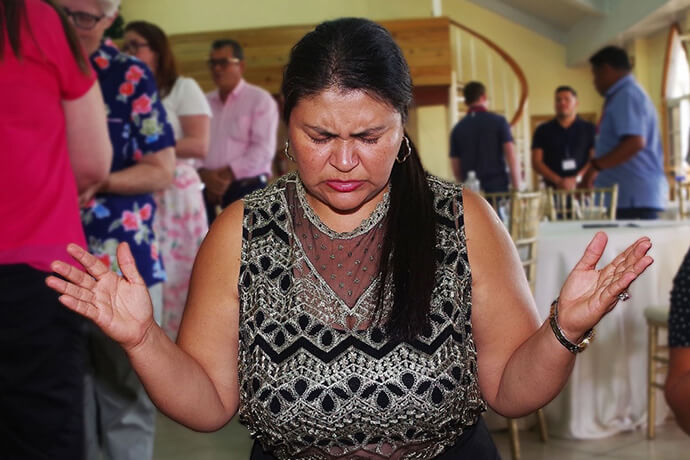 Sister Arely Rodríguez, a lay delegate to the annual meeting of the United Methodist Mission in Honduras, kneels in prayer after receiving the Eucharist during worship at the United Methodist Church at Nueva Era, home of the mission’s administrative offices. The March 18 meeting was the first in-person gathering for the mission since the COVID-19 pandemic. Photo by the Rev. Gustavo Vasquez, UM News.