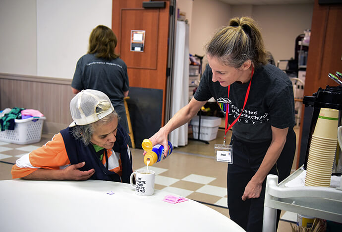 Volunteer Jessi Watkins (right) puts creamer in the coffee of an unidentified woman March 28 at First United Methodist Church of Austin. Volunteers look for opportunities to serve the women since they rarely experience it on the streets. Photo by Andrea Turner, UM News.