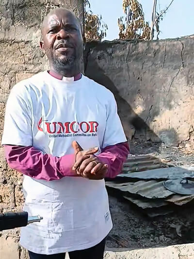 Bishop Ande I. Emmanuel prays outside a damaged home in one of the communities affected by the recent attack on predominantly Christian farmers in Karim Lamido, Nigeria. Photo by the Rev. Filibus Bakari Auta, UM News. 