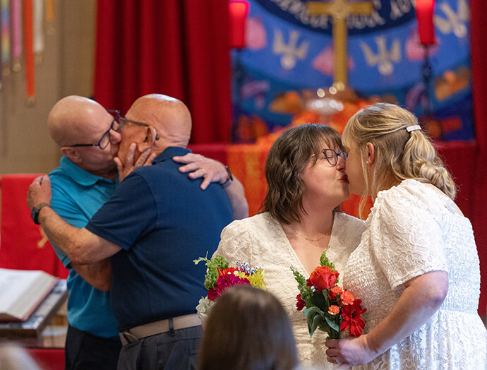 Couples kiss after renewing their wedding vows at Edgehill United Methodist Church in Nashville, Tenn. From left are John Brown, the Rev. Deen Thompson, Lindsey Dye and Laura Smotherman. They were among three couples who were previously unable to wed at their church home because of United Methodist bans that were overturned last year. Photo by Mike DuBose, UM News.