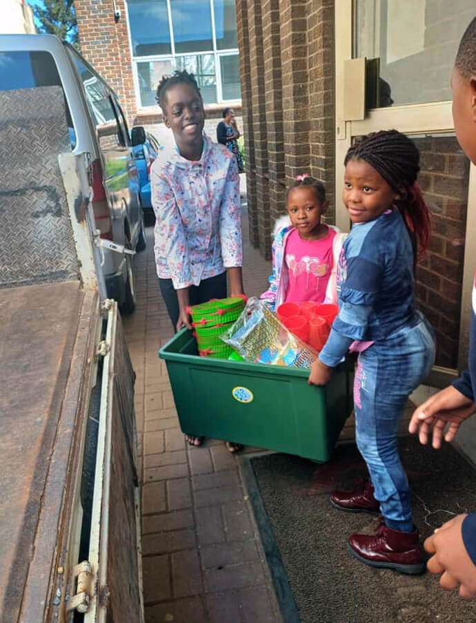 Maitaishe Gwara (de gauche à droite), Mecala et Chipiwa Zhungu transportent leurs cadeaux jusqu'à un véhicule qui les acheminera vers l'hôpital local de Harare, au Zimbabwe. Les membres du programme de l'école du dimanche de la Harare Inner-City United Methodist Church ont collecté 2 500 dollars pour offrir des cadeaux aux enfants du service de pédiatrie. Photo par Chenayi Kumuterera, UM News.