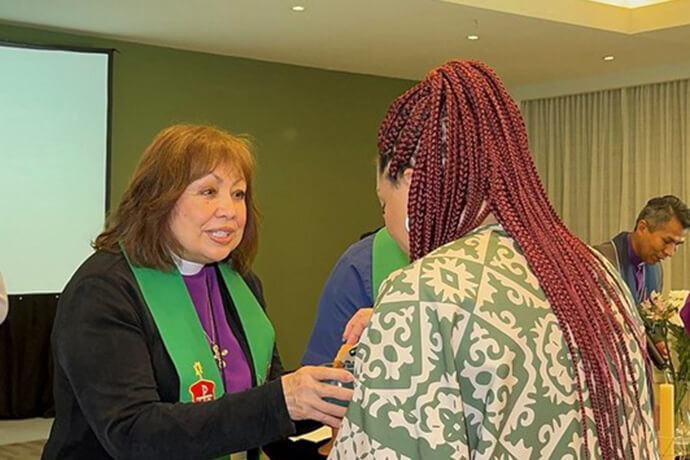Retired United Methodist Bishop Minerva Carcaño (left), leader of the “Holistic Relationship Strategy” with the churches in Latin America and the Caribbean, administers Holy Communion during the opening service of the consultation. 