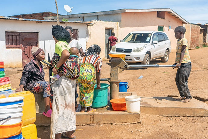 Des femmes et des enfants puisent de l'eau dans un puits au camp de réfugiés de Dzaleka au Malawi. Resurrection, une Église Méthodiste Unie multisite de la région de Kansas City, soutient un programme dans le camp qui fournit de la nourriture et un encouragement spirituel aux réfugiés, dont beaucoup sont confrontés à l'insécurité alimentaire et à la malnutrition. L'église a financé le forage il y a 10 ans pour fournir de l'eau potable au camp. Photo par Francis Nkhoma, UM News.
