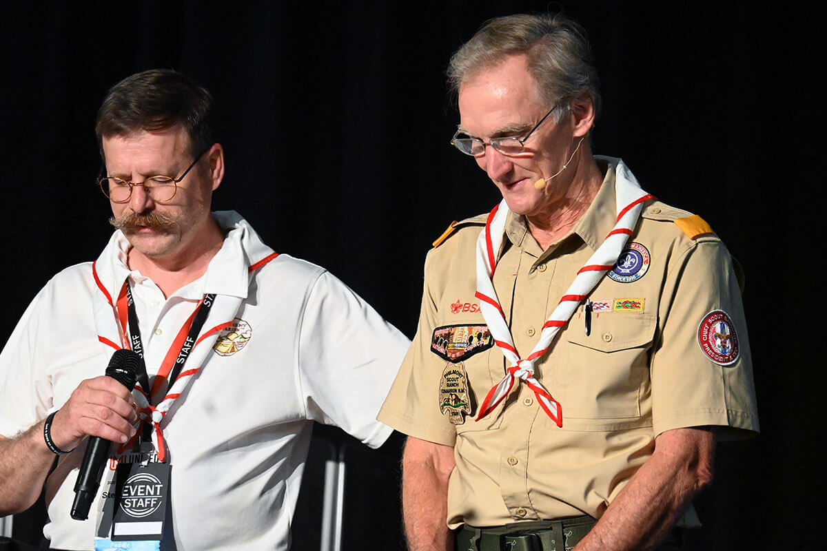 Steven Scheid (left), director of scouting ministry for United Methodist Men, bows his head in prayer Aug. 2 before introducing Roger Krone (right), CEO of Scouting America. Krone spoke Aug. 2 about scouting during the 2025 National Men’s and Scouting Ministry Gathering at Epworth-by-the-Sea, a United Methodist retreat center in St. Simons Island, Ga.  Photo by Jim Patterson, UM News.