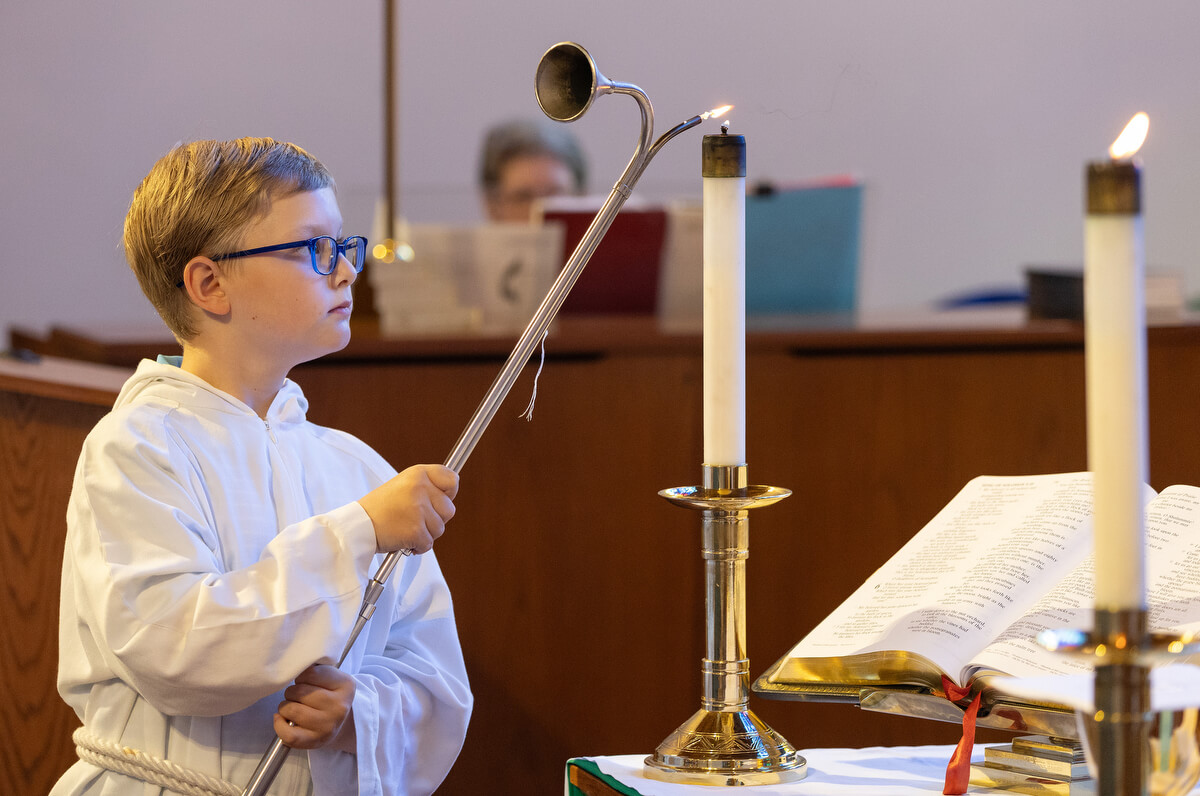 Acolyte Andersen Meyer lights the altar candles at St. Luke’s United Methodist Church. Photo by Mike DuBose, UM News.