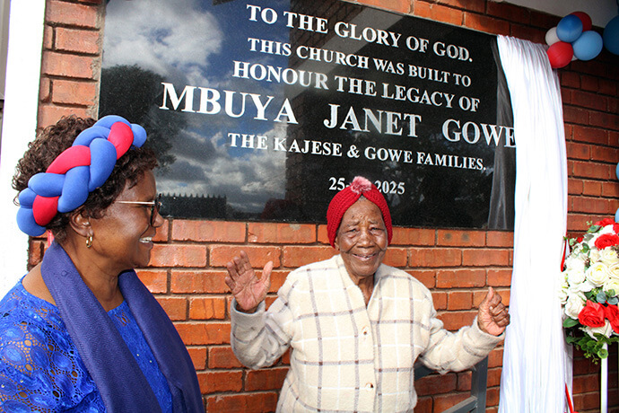 United Methodist Janet Gowe stands in front of the sign for the new Nzira Sanctuary, which is dedicated in her honor. Over the years, Gowe encouraged her son to build a sanctuary where they could gather and praise God. Photo by Kudzai Chingwe, UM News.