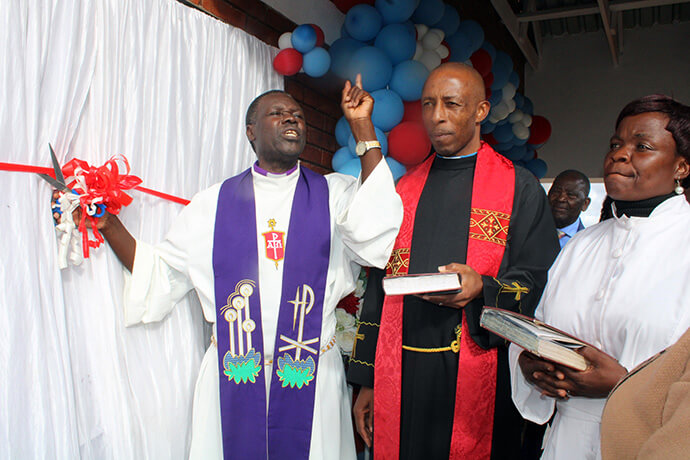 Bishop Gift K. Machinga (left) cuts the ribbon during the dedication of Nzira Sanctuary in Murewa, Zimbabwe. The sanctuary was dedicated to 102-year-old Janet Gowe who pushed to have a United Methodist church built in her circuit for over 30 years. Next to the bishop is the Rev. Paul Mazumba, Murewa Uzumba Maramba Pfungwe District superintendent. Photo by Kudzai Chingwe, UM News.