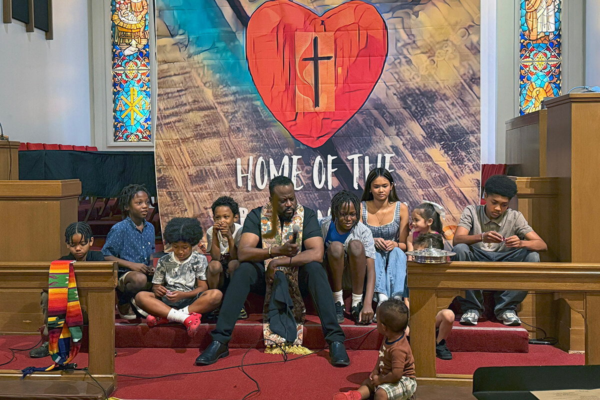 The Rev. J. Andre Wilson (center) shares a message with children during Altadena United Methodist Church’s first Sunday worship service at its new temporary home on the campus of the former First United Methodist Church of San Gabriel, Calif. Altadena is one of two United Methodist churches destroyed by wildfires in January. Photo courtesy of Heather Wilson.