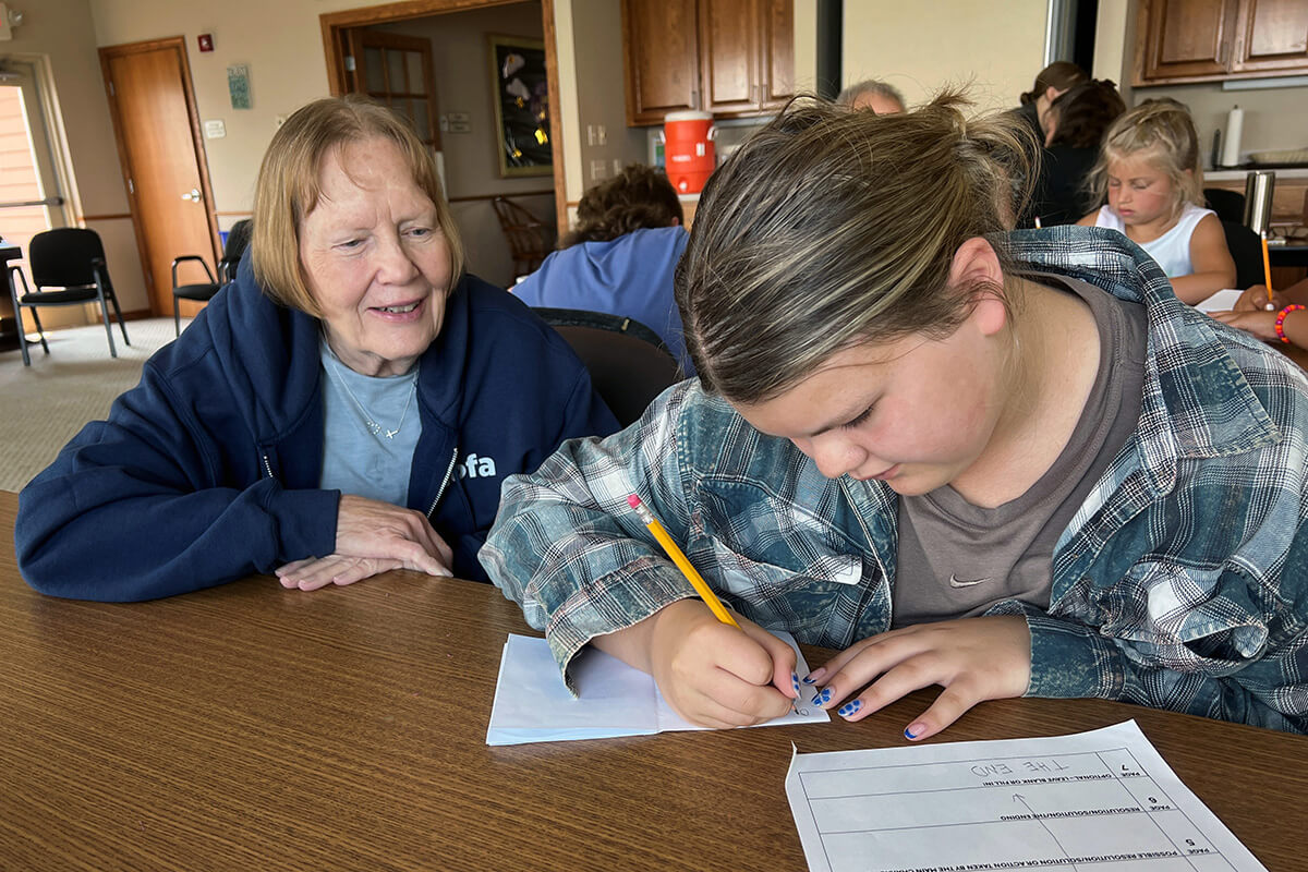 Donnette Gering helps her granddaughter Amelia Polreis write a story as part of Grandparents and Me Camp at Lake Poinsett in Arlington, South Dakota. Photo by Lilla Marigza, UM News.