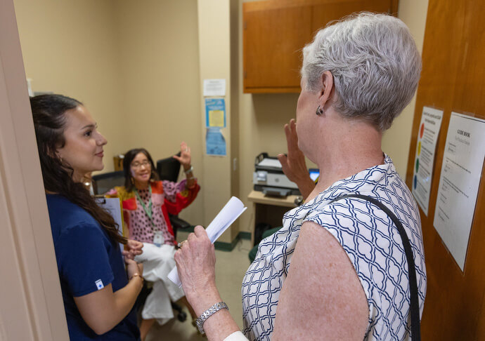Dr. Susan Berry (right) greets Dr. Betty Lo-Blais (center) during a tour of Luke’s House. Berry was the clinic’s first medical director and Lo-Blais is director of the medicine pediatrics resident program at Louisiana State University. At left is medical student Karla Gallegos Díaz. Photo by Mike DuBose, UM News.